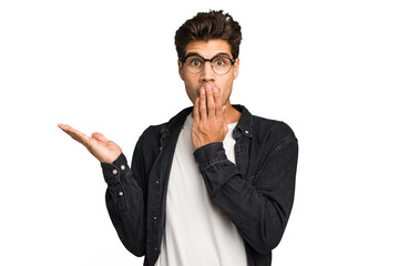 Young caucasian handsome man isolated impressed holding copy space on palm.