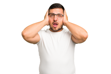 Young caucasian man isolated covering ears with hands trying not to hear too loud sound.