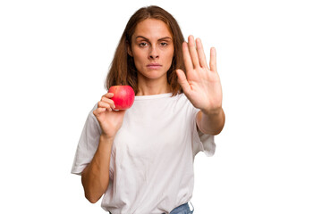 Young caucasian woman holding a red apple isolated standing with outstretched hand showing stop sign, preventing you.