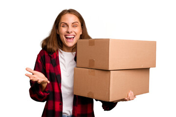 Young caucasian woman moving while picking up a box full of things isolated receiving a pleasant surprise, excited and raising hands.