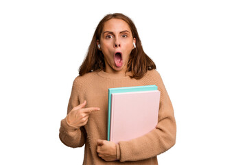 Young student woman holding a books isolated pointing to the side