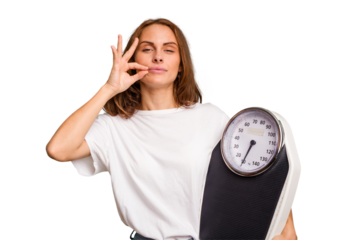Young caucasian woman holding a scale and measure tape isolated with fingers on lips keeping a secret.