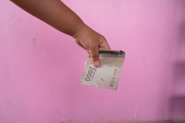 selective focus on the Indonesian two thousand rupiah banknote held by an Asian girl