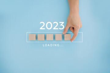 Female hand putting wooden cube for countdown to 2022. Loading year from 2022 to 2023. New year...