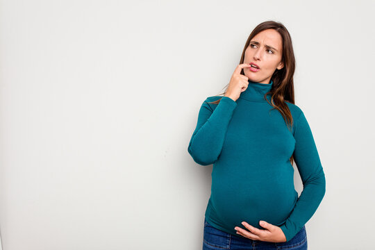 Pregnant caucasian woman isolated on white background relaxed thinking about something looking at a copy space.