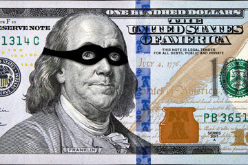 Portrait of Benjamin Franklin in a black mask of a robber on a banknote of one hundred dollars....