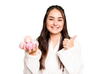 Young caucasian woman holding aromatic balls for bathtub isolated on green chroma background smiling and raising thumb up