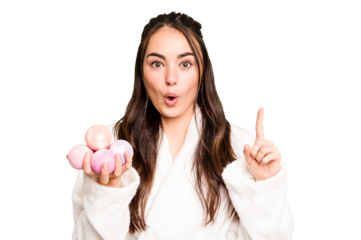 Young caucasian woman holding aromatic balls for bathtub isolated on green chroma background having some great idea, concept of creativity.