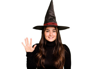 Young caucasian woman dressed as a witch isolated on green chroma background smiling cheerful showing number five with fingers.