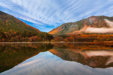 秋の大滝川ダムに映る紅葉の山々と青空,