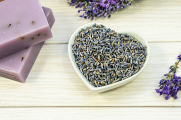 Dried lavender flowers in a bowl on a wooden background. Top view, place for text.