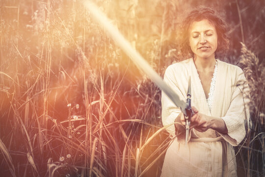 Beautiful woman in nature with a sword in her hand.