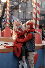 Cute young couple in love having romantic date on New Year's Christmas winter fair city street. St...