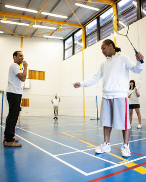 Sports Students: Badminton Mixed Doubles. Teenagers in their college gym under the supervision of their teacher. From a series of related images.