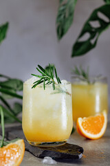Cold summer refreshing orange and ice drink with a sprig of rosemary