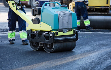 Road construction equipment flattening and smoothing asphalt black top lane