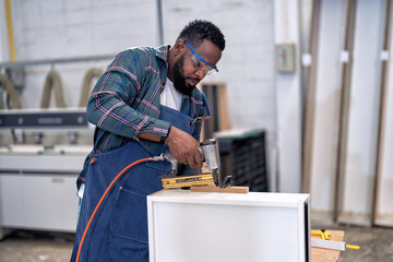In work place carpenter man concentrate working using pneumatic nail gun drive nail to the wood