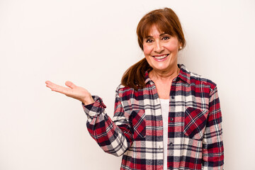 Middle age caucasian woman isolated on white background showing a copy space on a palm and holding...