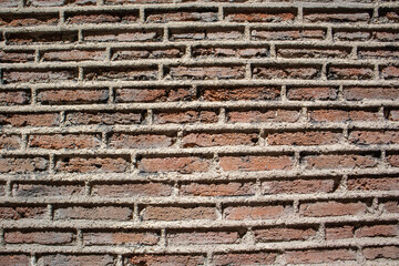 Wall facade of red brick building with contrasting shadows on sunny day. Abstract background, pattern of brickwork. Architectural element. Construction, building fragment сoncept. Old grunge stones.