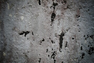 A weathered concrete wall with cracks and peeling paint, showing signs of age and decay.