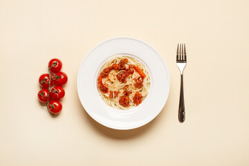 top view of pasta with meat in white plate near fork and cherry tomatoes on beige background