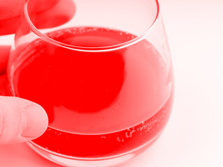 In the hand of an octel in a glass in red colors. Closeup
