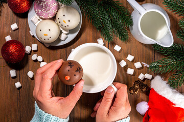 Making winter hot drink, preparation funny Christmas characters with hot chocolate bomb. Homemade hot chocolate cocoa balls made with Christmas snowman, reindeer, snowflake decor