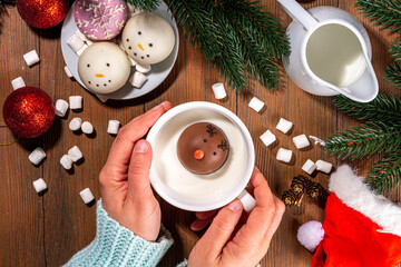 Making winter hot drink, preparation funny Christmas characters with hot chocolate bomb. Homemade hot chocolate cocoa balls made with Christmas snowman, reindeer, snowflake decor