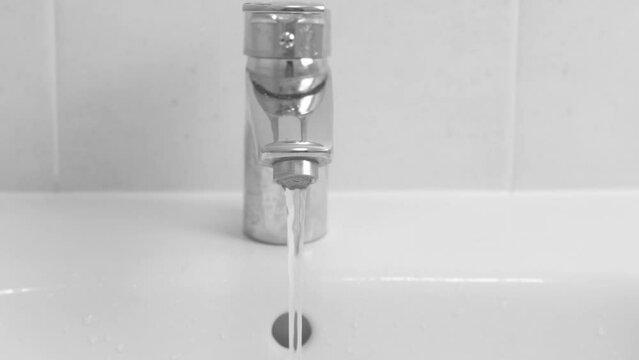 Close-up of a water faucet with flowing water in the bathroom