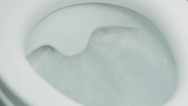 Close-up of a toilet in which water is flushed