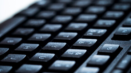 Close up detail view of desktop computer keyboard with light shining on keys. Computer key in macro with Enter key on keyboard. Night work. Macro.