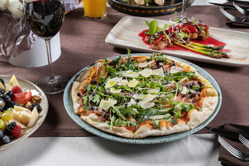 Sliced pizza with meat jamon and arugula. Sprinkled with Parmesan cheese.