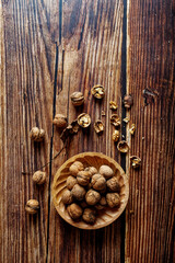 Walnuts in a wooden bowl on a rustic wooden table. Overhead shot with negative space.