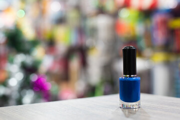 Blue nail polish placed on a brown table, bright light shines on, behind a large number of blurred...