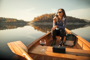 Young woman enjoy outdoors in canoe with glass of red wine