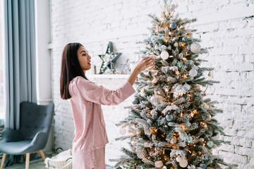 Asian woman decorating christmas tree at home