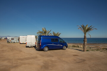 Fototapeta na wymiar Kompaktes Reisemobil beim Wildcampen am Meer mit Palmen