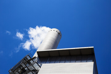 Rauchender Schornstein einer Fabrik mit blauem Himmel