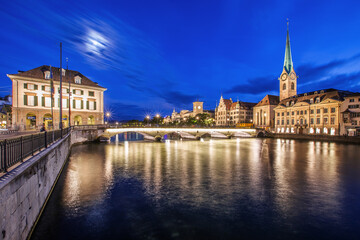 Stadt Zürich in der Schweiz bei Nacht mit dem Fluss Limmat im Vordergrund.