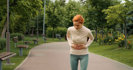 Woman has stomachache during workout. Female stops exercise due to stomachache illness. Sickness...
