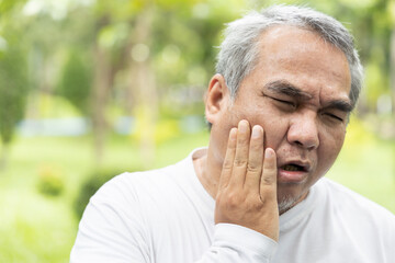Obraz premium Old asian senior man suffering from toothache, tooth decay, tooth sensitivity, teeth grinding problem; oral health care concept