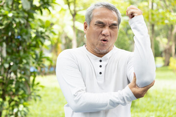 sick old senior man suffering from elbow joint pain; concept of tennis elbow or golfer’s elbow...