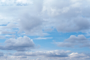 Lots of cumulus clouds far on horizon on blue daylight sky. Light blue sky with clouds, fresh atmosphere. White fluffy clouds running across a sunny blue sky. Wonderful summer air