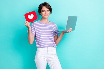 Photo of positive lady hold red paper heart card enjoy using new gadget recommend netbook empty space isolated on cyan color background