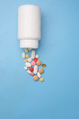 colorful medical pills spilling on blue background 