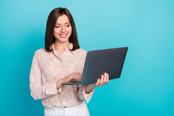 Photo of young successful positive lady wear pink shirt hold laptop typing professional programmer codder isolated on bright blue color background