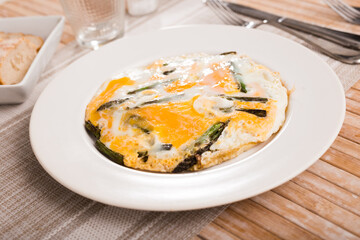 Closeup of fried eggs with asparagus at plate