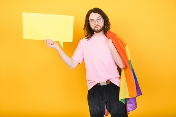 Fototapeta na wymiar Gay man wearing bright pink top hold rainbow striped flag isolated on colored background studio portrait. People lifestyle fashion lgbtq concept
