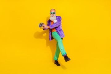 Full body portrait of excited crazy granddad arms hold disco ball dancing isolated on yellow color background