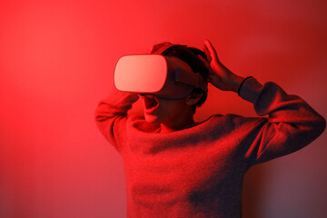 Young girl watching a movie on VR headset on red background